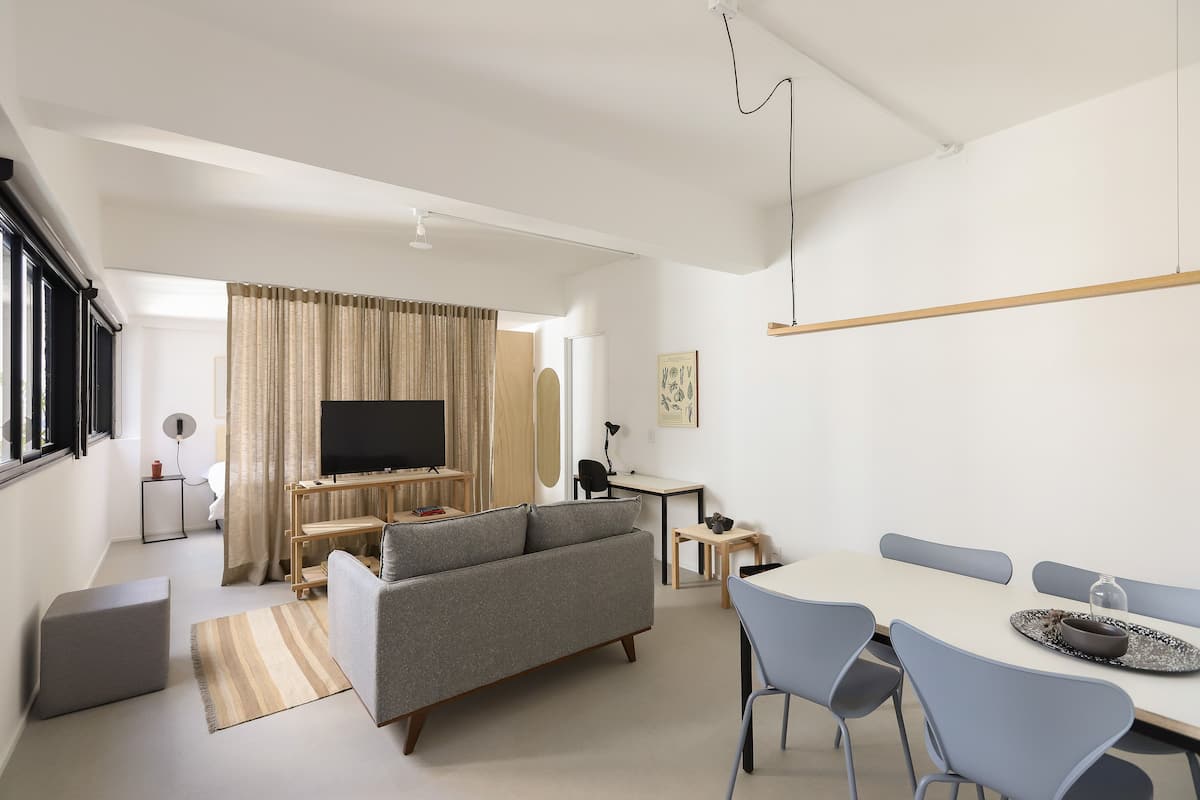 A modern living room with a sofa, TV, and dining table.
