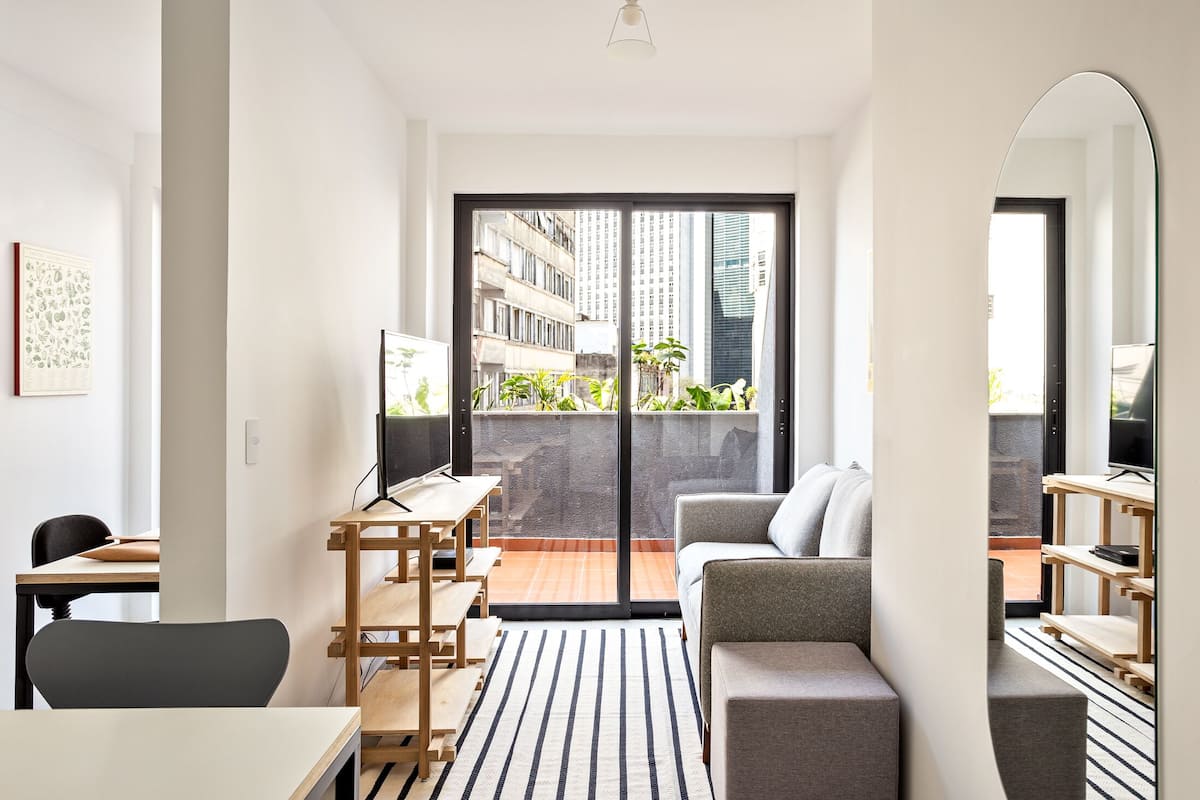 A modern living room with a sofa, a TV, and a dining area with a table and chairs.