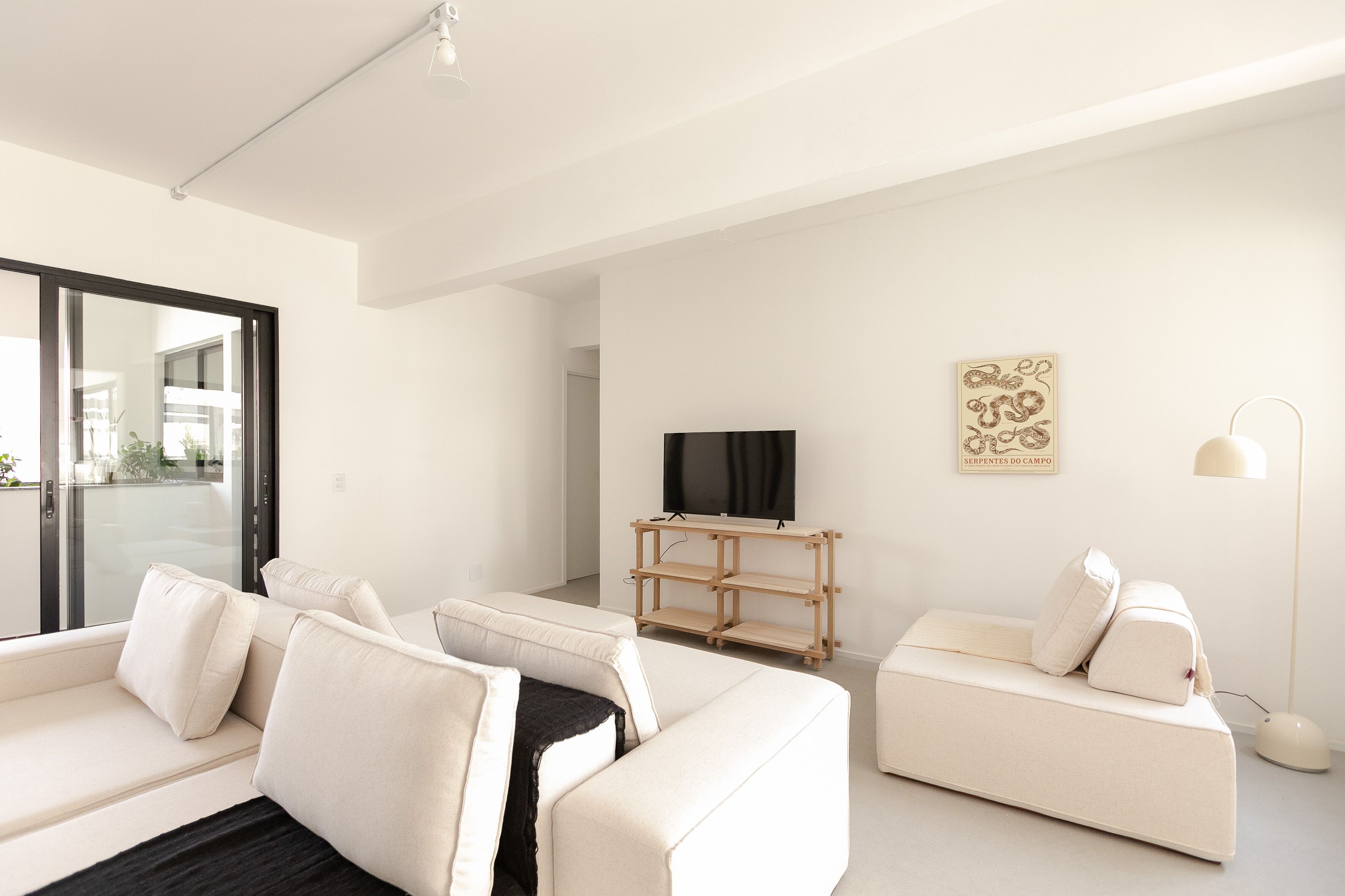 A modern living room with a sofa set, a TV on a wooden stand, and a floor lamp.