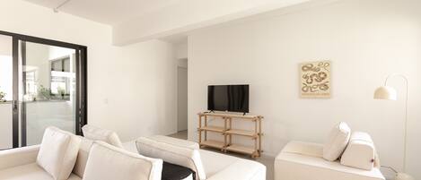 A modern living room with a sofa set, a TV on a wooden stand, and a floor lamp.