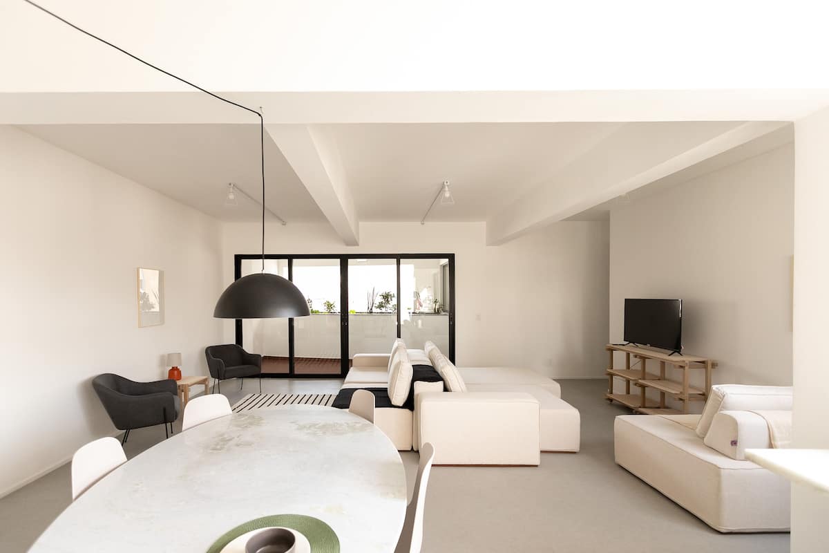 A modern living room with a large round table, sofas, and a TV stand.