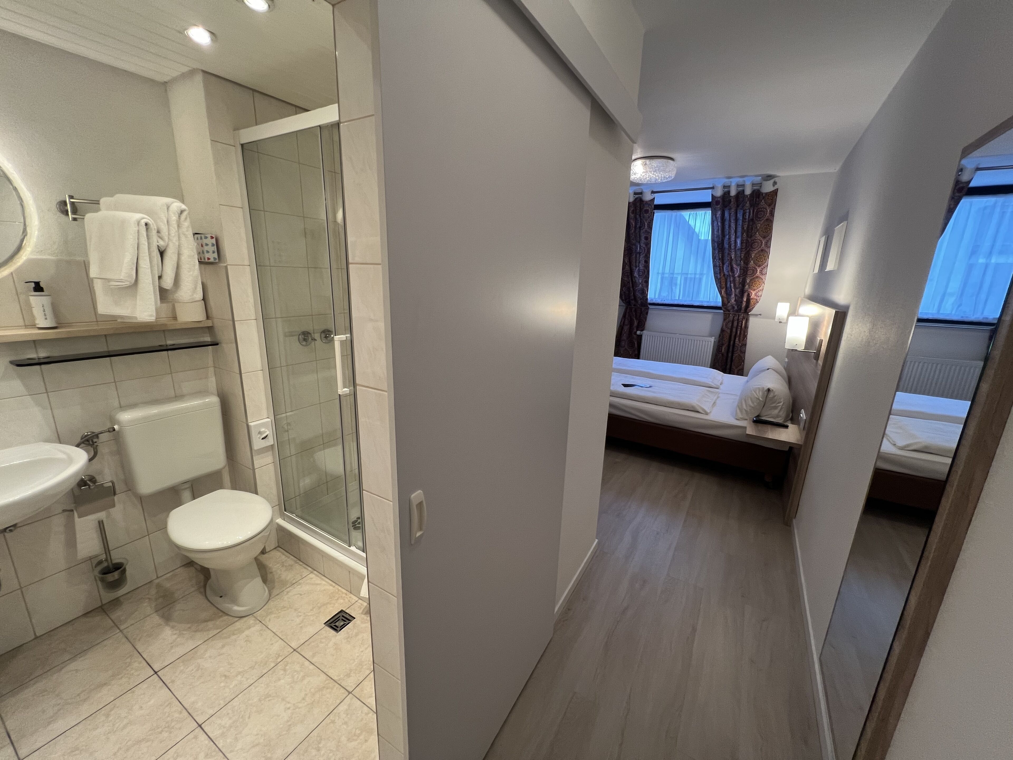 A modern bathroom with a glass shower enclosure, a toilet, and a sink.