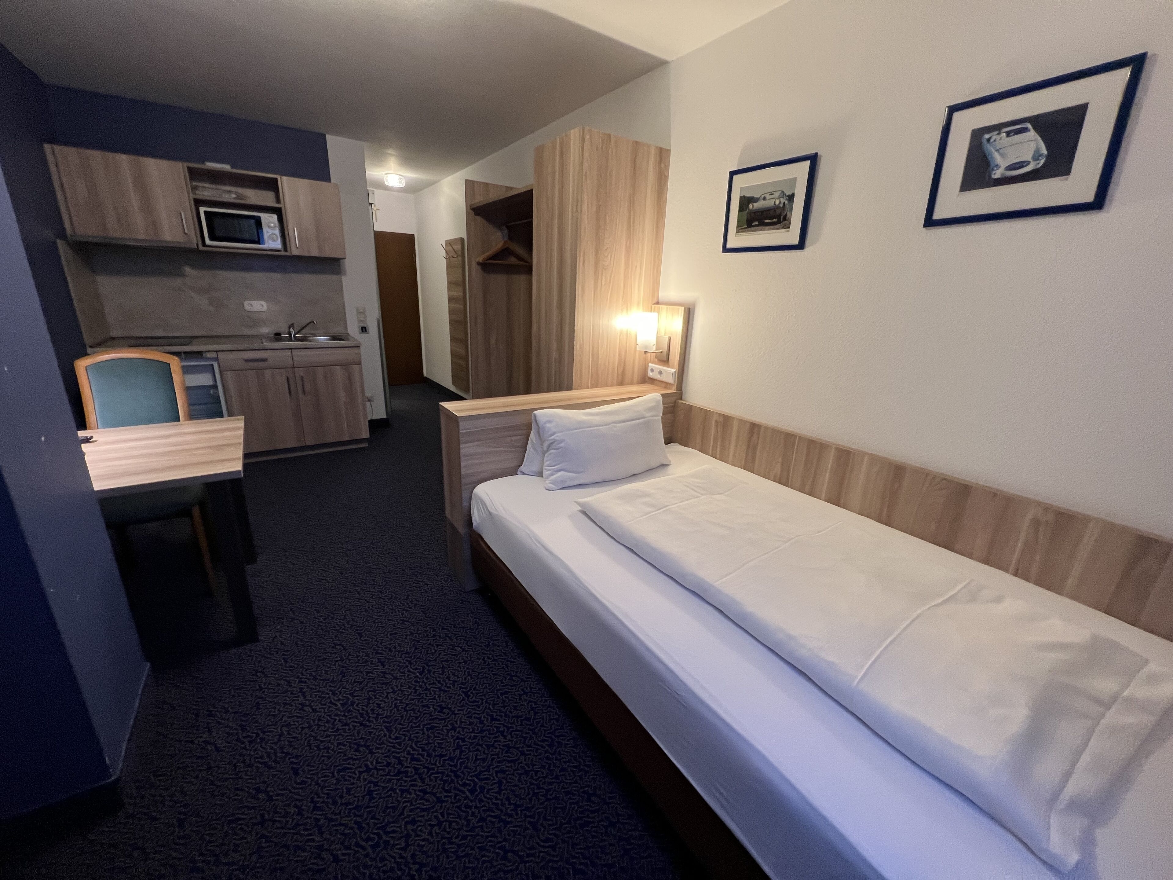 Une chambre d’hôtel équipée d’un lit, d’un bureau, d’un four à micro-ondes, d’une armoire et d’un tableau encadré au mur.