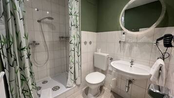 A bathroom with a shower, toilet, sink, and a mirror.