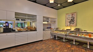 Un área de bufé con diversas opciones de comida, una estación de café y una barra con el menú.