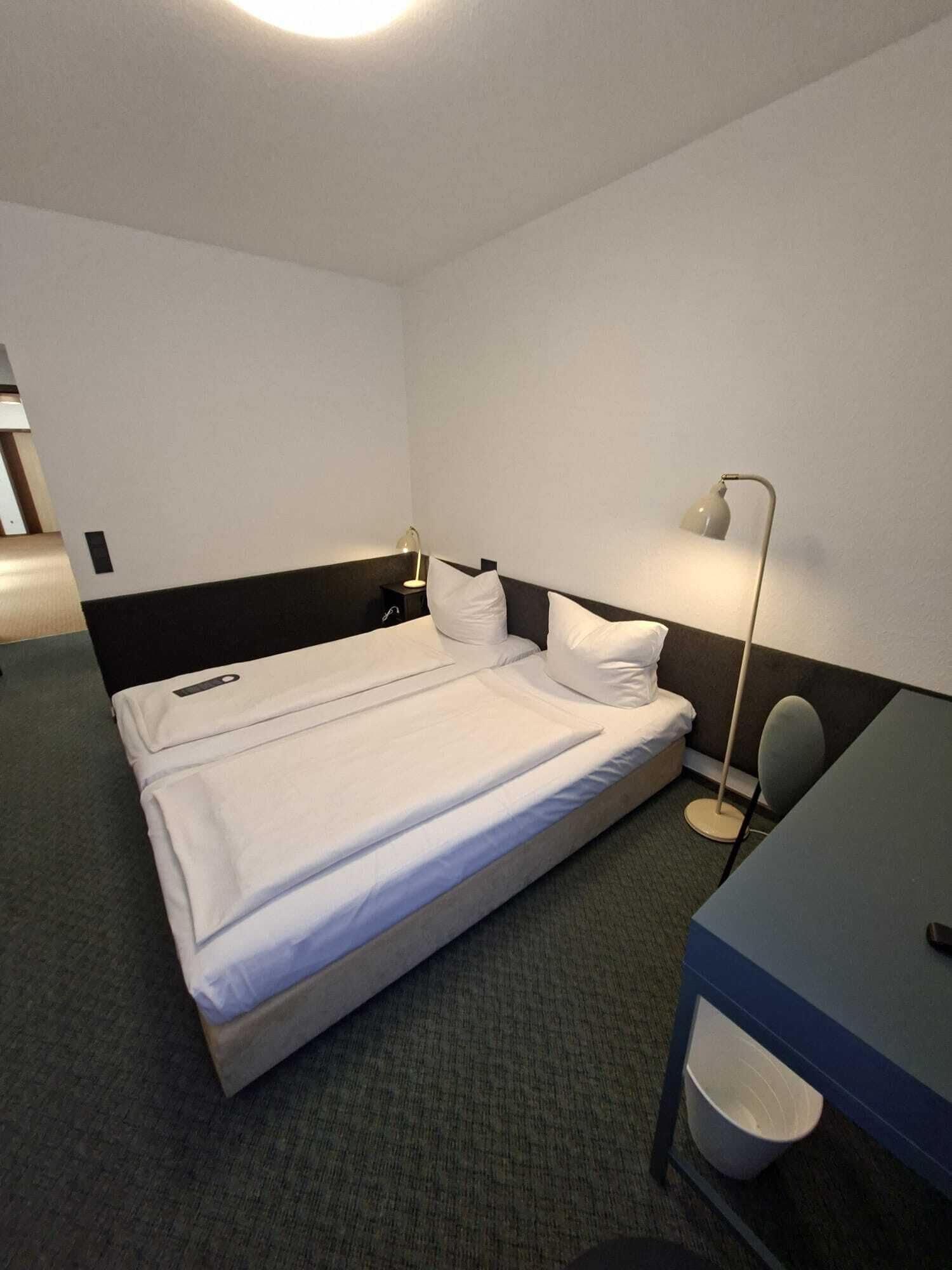 Una camera d'albergo con un letto, comodini, una scrivania e una sedia.