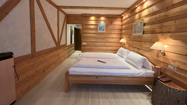 Un dormitorio con paneles de madera, una cama, lámparas de noche y un cuadro enmarcado en la pared.