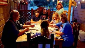Un grup de persones assegudes al voltant d'una taula de fusta en un restaurant amb interior de fusta i vistes a l'exterior.