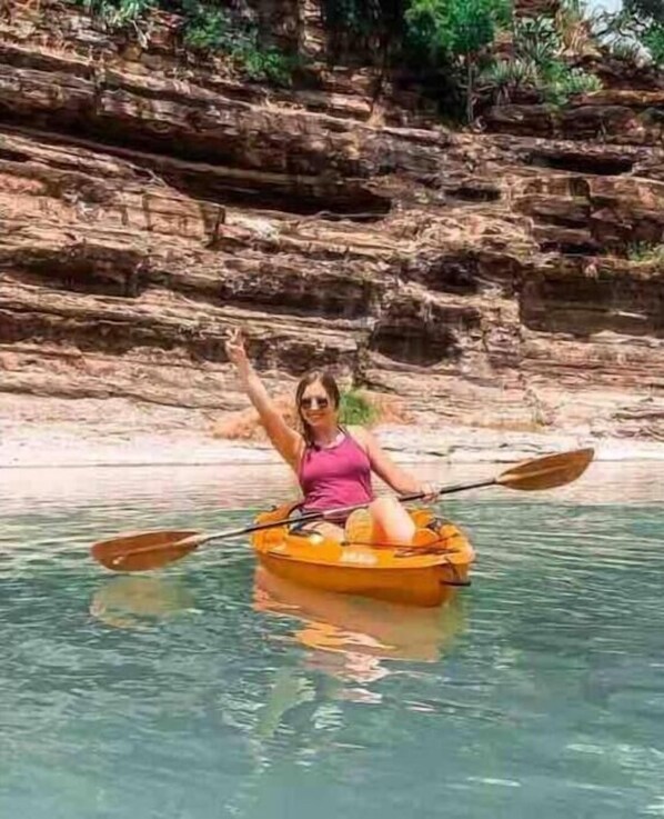 A person kayaking in clear water with rocky cliffs in the background. - LLANO RIVER CABINS (Mason)