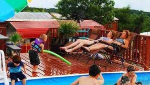 Zona de piscina amb gandules i un edifici amb teulada vermella al fons.