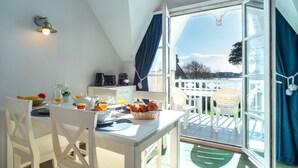 Une salle à manger lumineuse, avec une table mise pour le petit-déjeuner, une vue sur l’extérieur et un ventilateur de plafond.