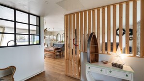 A room with a wooden partition, a desk with drawers, a chair, and a large window. - La perle de mer - Charmante maison avec jacuzzi (Erquy)