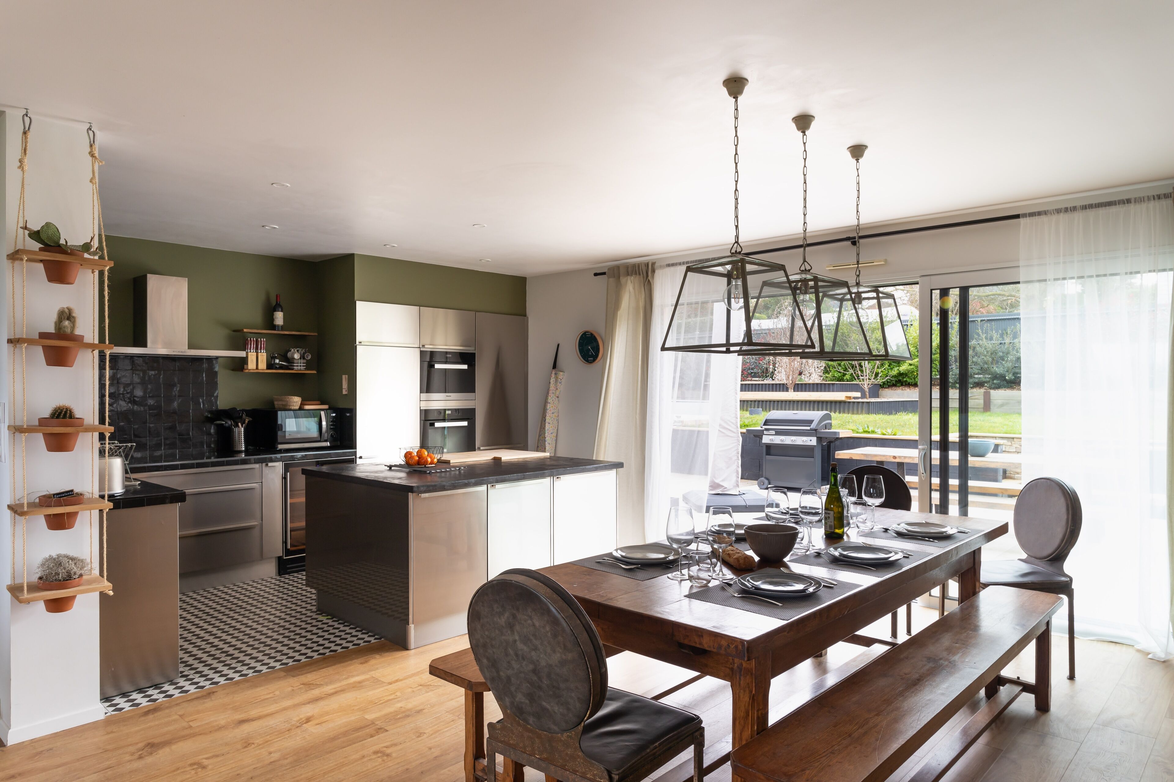 Una cocina moderna con una isla central, mesa de comedor de madera y bancos.