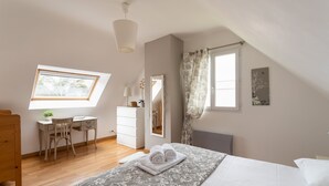 Ein Schlafzimmer mit Bett, Schreibtisch, Stuhl, Kommode und einem Fenster mit Vorhängen.