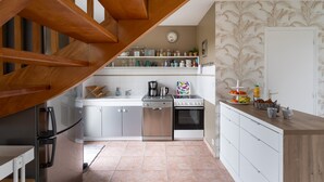 Eine Küche mit Holzboden, Edelstahlgeräten, weißen Schränken und einer Wand mit Muster.