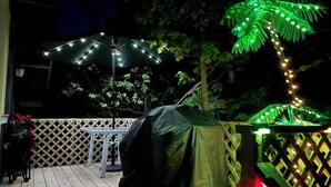 Une terrasse extérieure avec une table et des chaises abritées, entourée d’une clôture en bois et d’un palmier.
