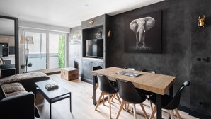 A modern living room with a dining area, a kitchen, and a large window.
