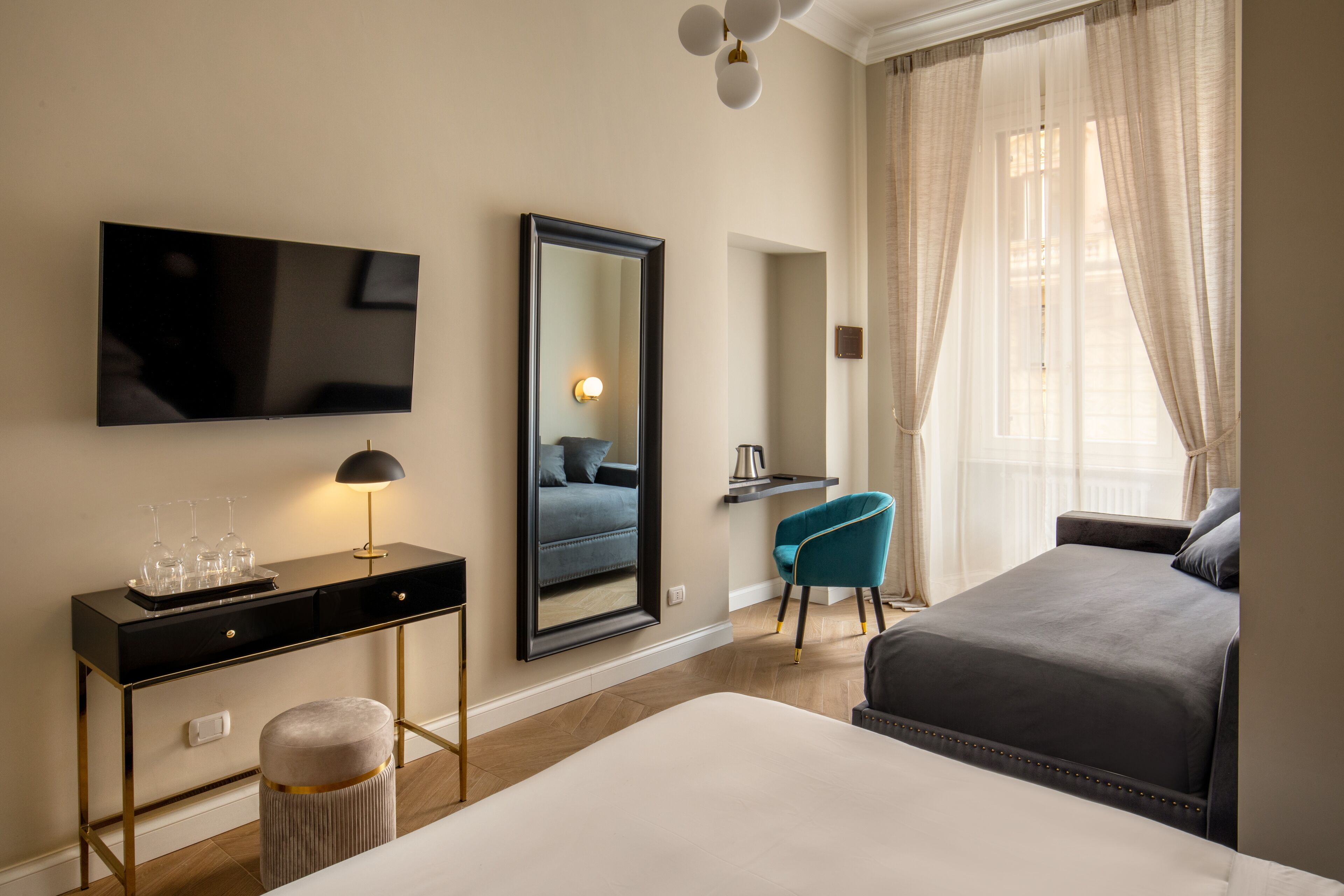 Quarto de hotel com uma cama grande, uma escrivaninha com televisão de tela plana, uma cadeira e um espelho.