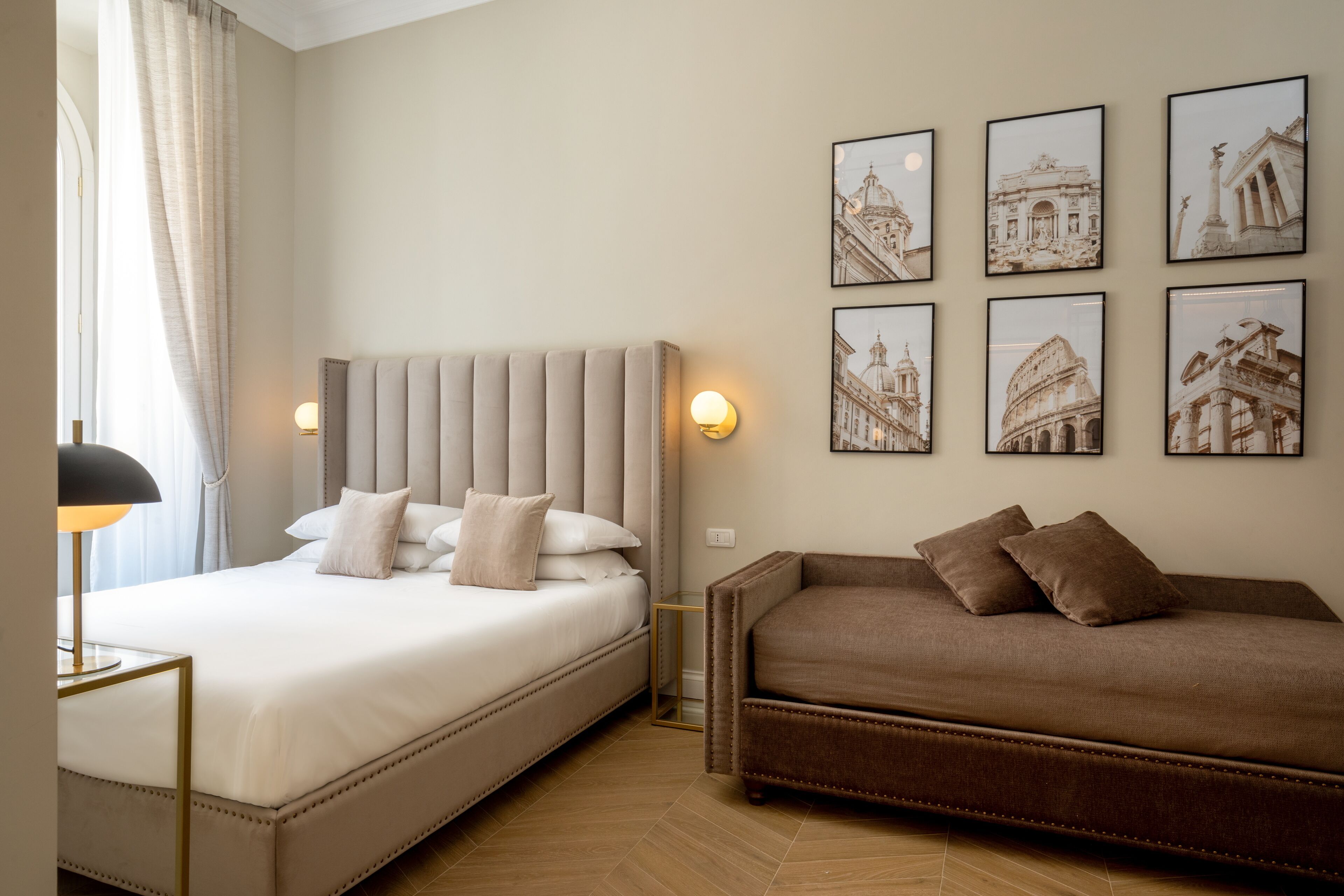 A hotel room with a large bed, a sofa, and wall-mounted artwork.