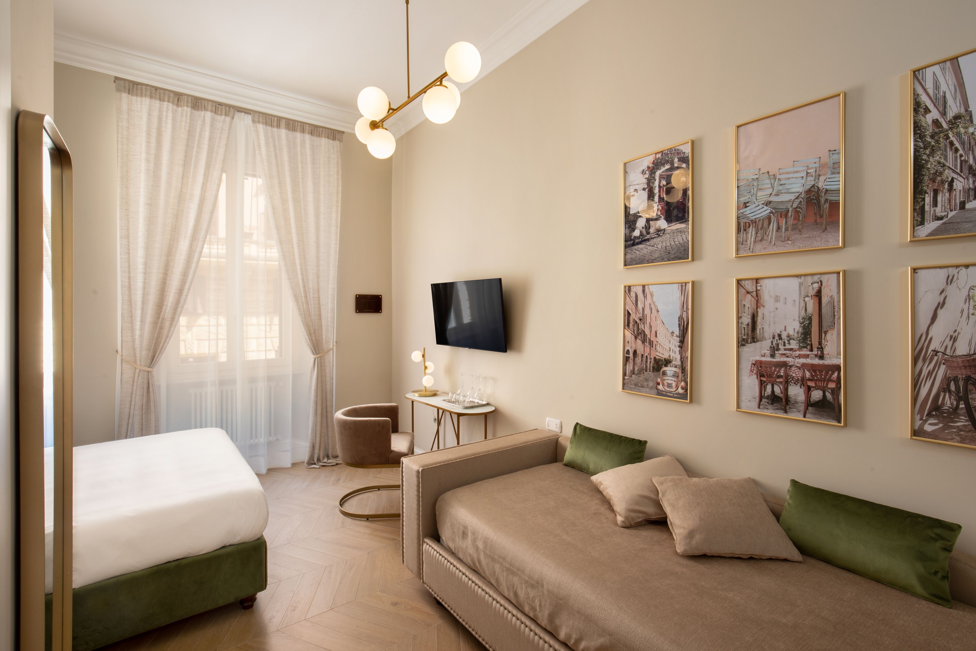 A room with a bed, a sofa, a TV, and artwork on the walls.