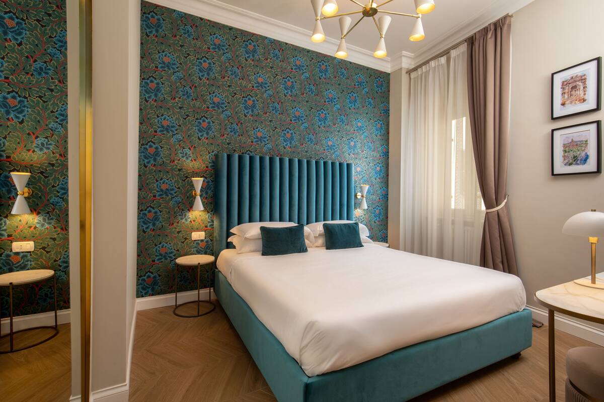 Une chambre d’hôtel avec un grand lit, une tête de lit, deux tables de chevet, un bureau et une chaise.