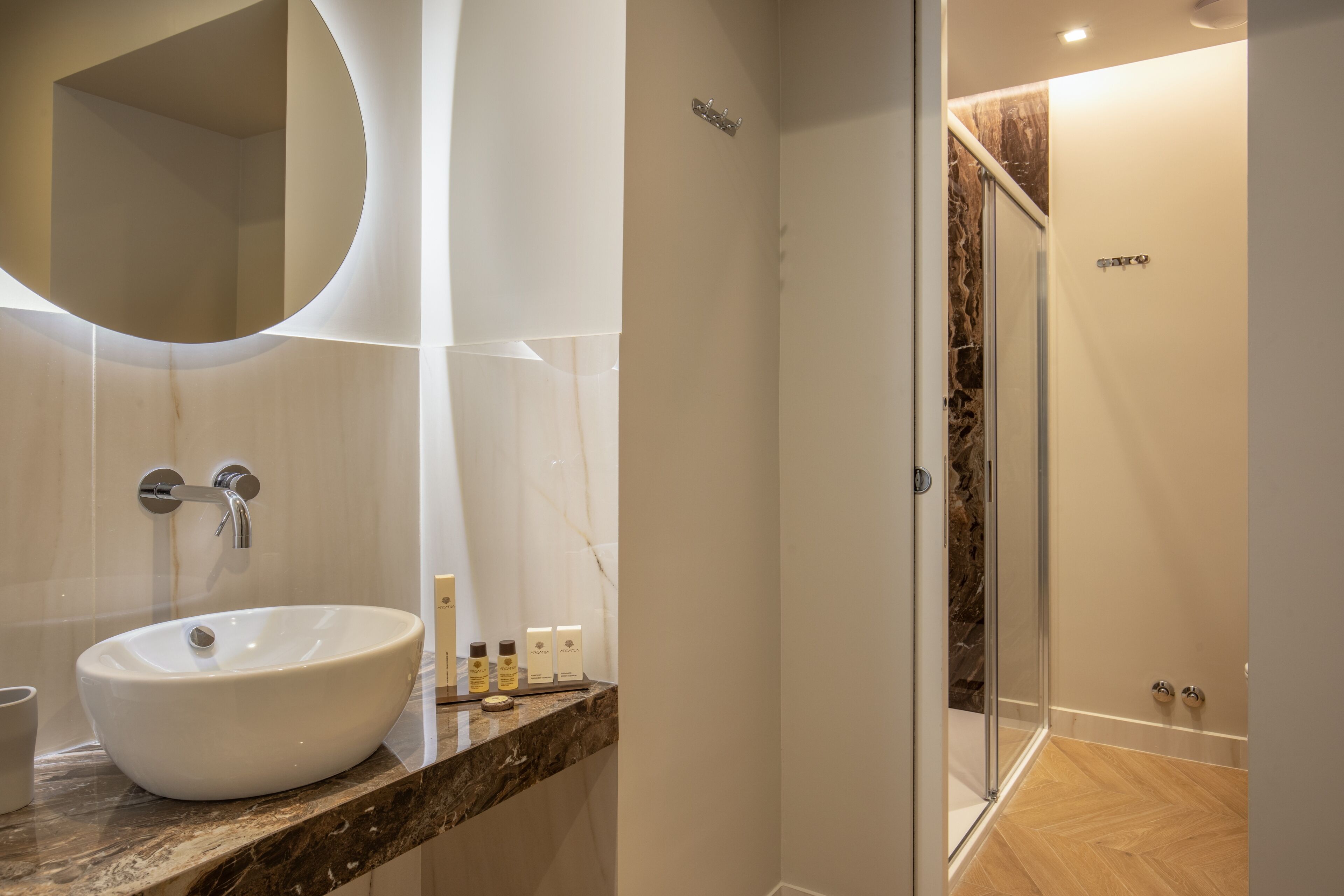 A modern bathroom with a large oval sink, a glass shower enclosure, and a marble countertop.