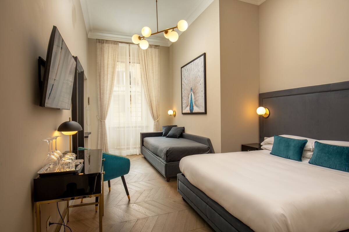Une chambre d’hôtel avec un lit, un bureau doté d’une lampe, une chaise, un canapé et un tableau au mur.