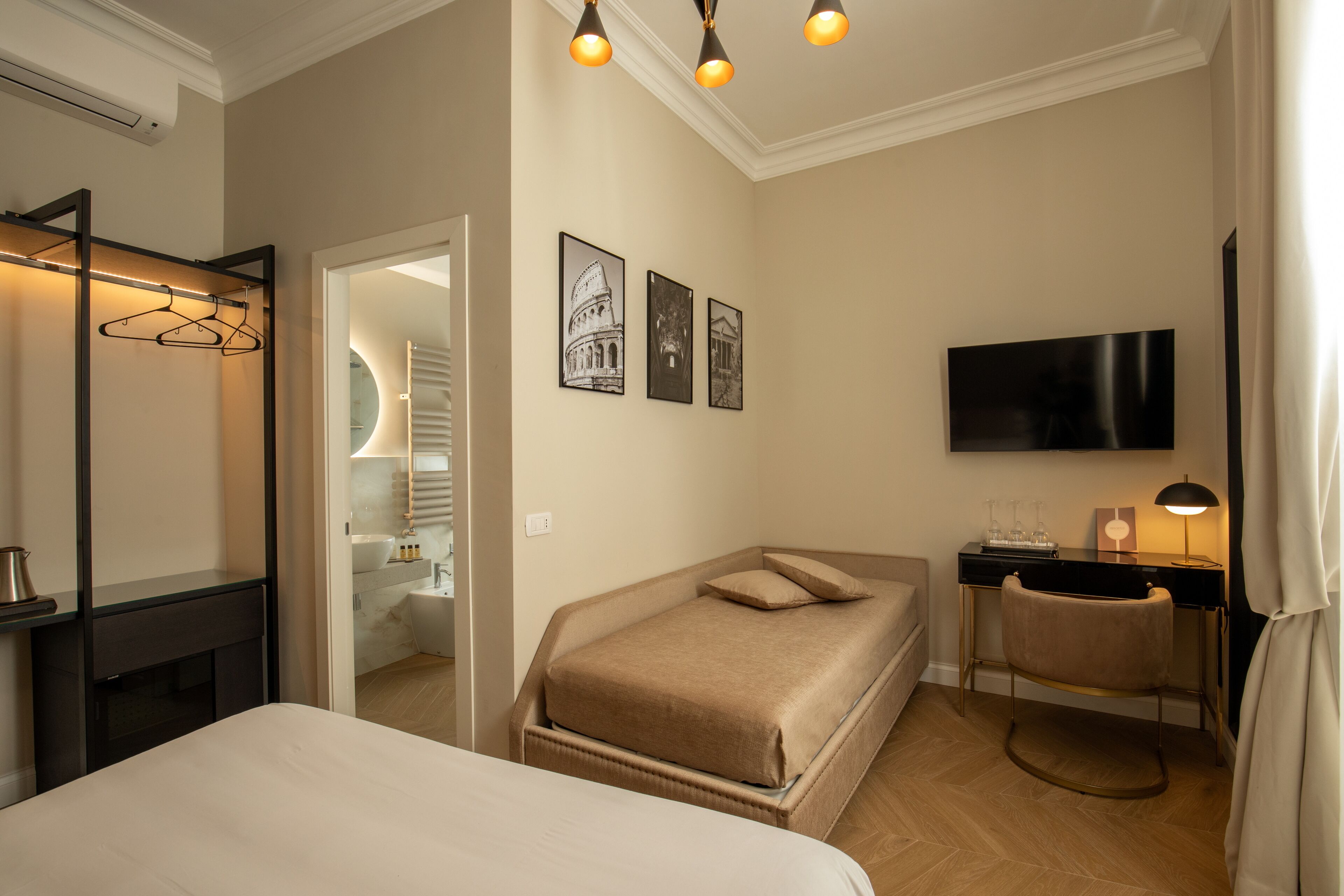 A hotel room with a bed, a desk, a chair, a TV, and a wardrobe.