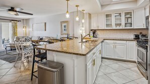 A modern kitchen with white cabinets, a granite countertop, and a built-in oven. - Arena De Madeira 502- Premier (Madeira Beach)