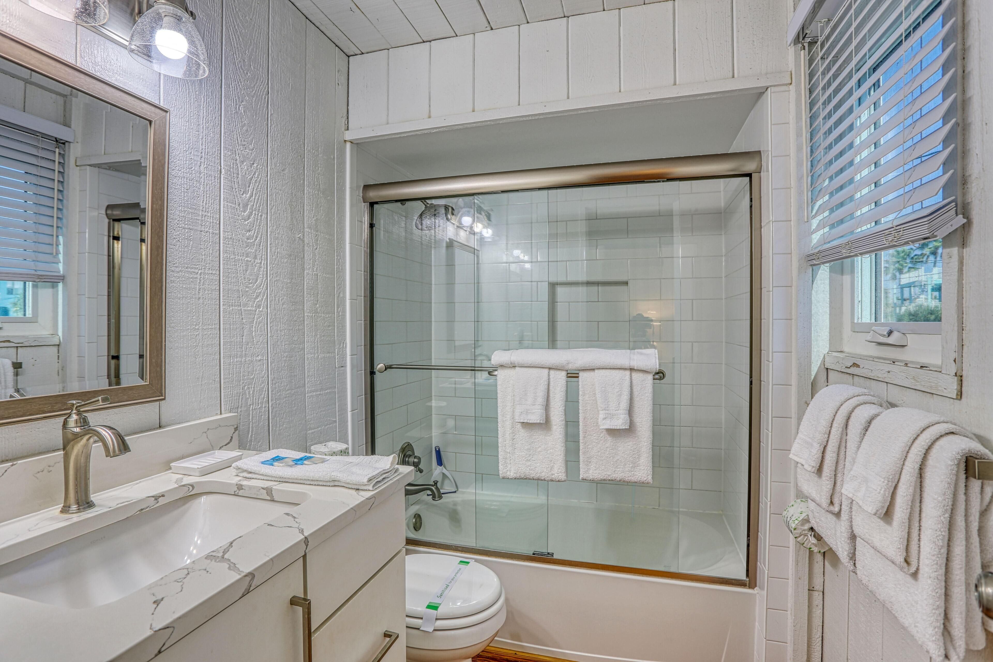 A bathroom with a glass-enclosed shower, a sink with a mirror, and a toilet.