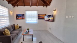 A living room with a sofa, a coffee table, and a TV mounted on the wall. - Safe & Spacious 2 BR Apt, Budget Friendly on South
 (Oistins)