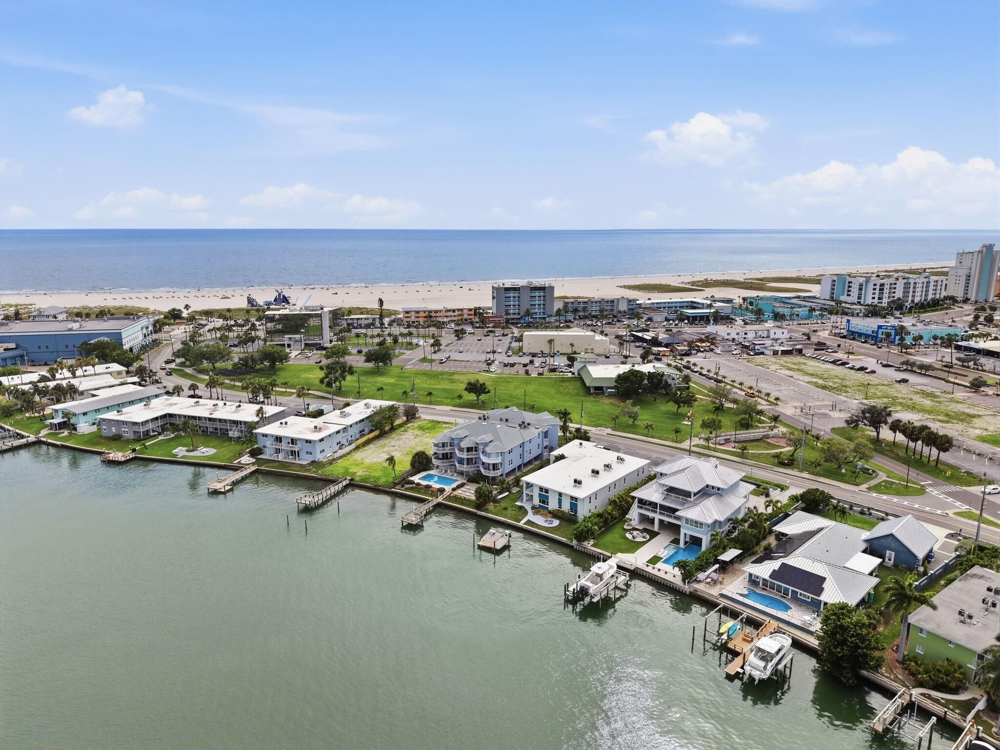 Luchtbeeld van een kustplaats met een jachthaven, gebouwen en een strand.