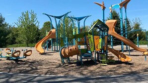 A playground with various play structures including slides and climbing areas.