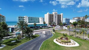 Un hôtel situé au bord d’une route sinueuse, entouré de palmiers et offrant une vue sur la plage.