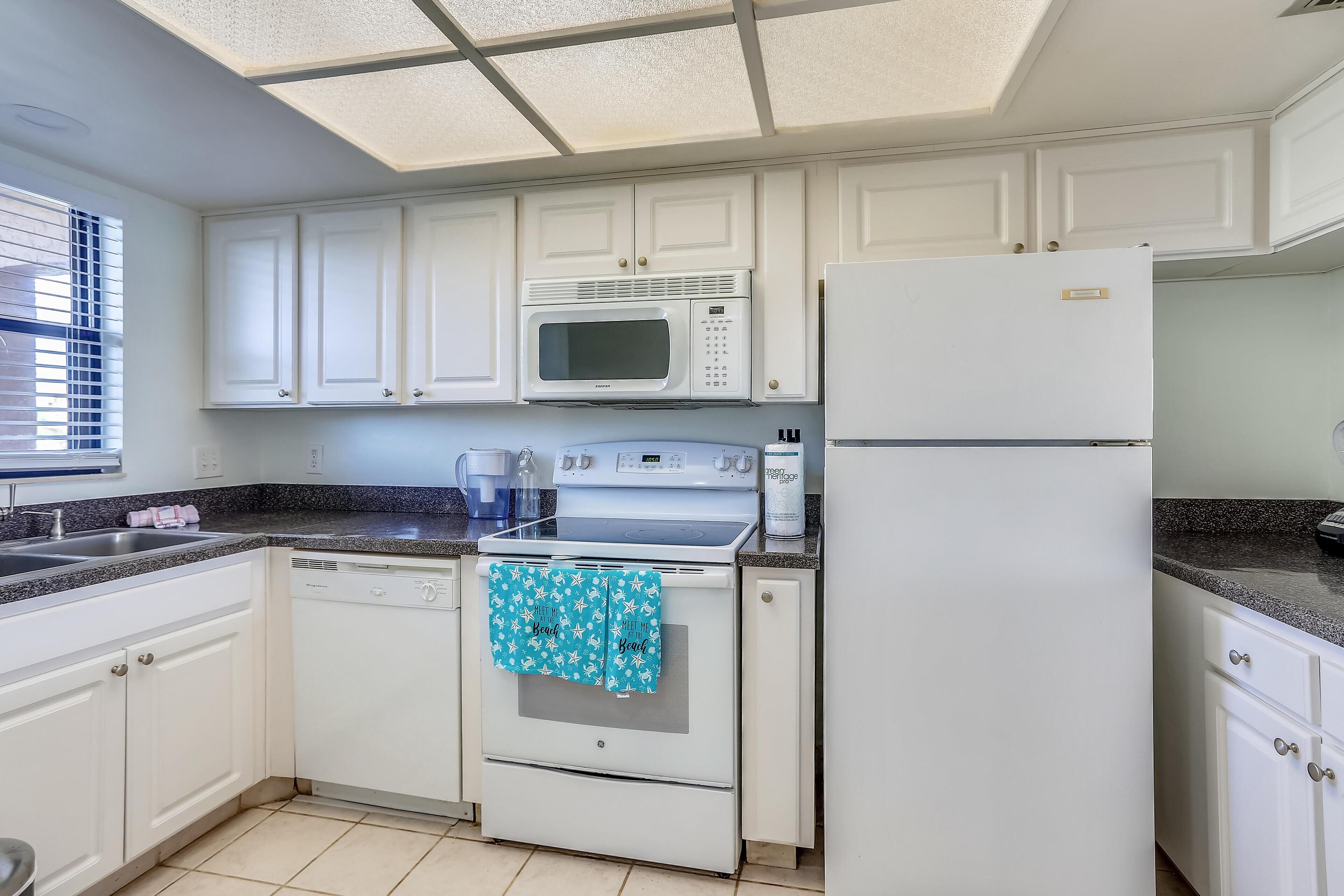 A kitchen with white cabinets, a microwave, a refrigerator, and a dishwasher.