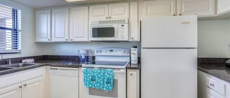 A kitchen with white cabinets, a microwave, a refrigerator, and a dishwasher.