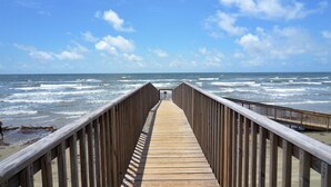 A wooden boardwalk leading to the ocean with waves crashing in the background. - Sandy Views - Step Right onto the Sand at Seascape Resort 2/2 condo (Galveston)