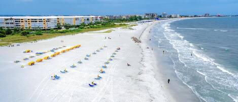 Una playa con hileras de sombrillas y un hotel al fondo.