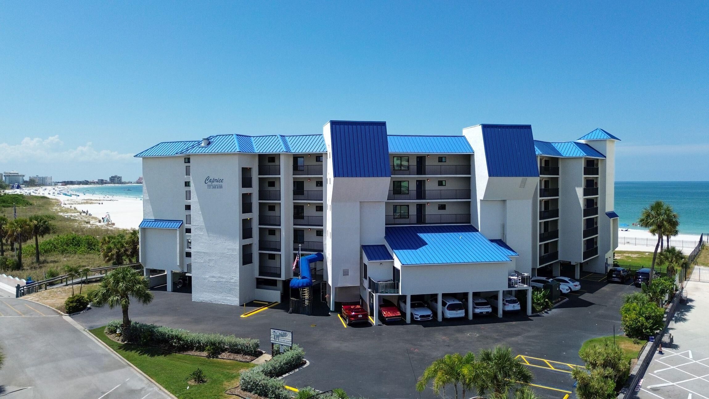 A multi-story hotel with a beach view, parking, and a pool area.