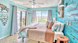 A bedroom with a bed, a ceiling fan, a window with curtains, and a sign for 'Resort Rentals'. - Caprice 306 (St. Pete Beach)