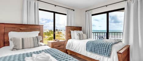 Habitación de hotel con dos camas, cabecera de madera, vista a la playa y balcón.