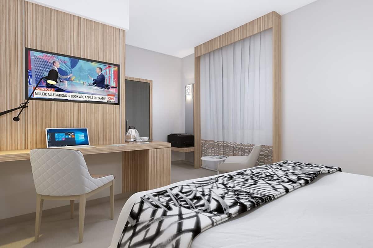 A modern hotel room with a bed, a desk, a chair, a TV, and a window with curtains.