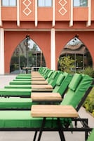 Una piscina al aire libre, sombrillas, sillones reclinables de piscina