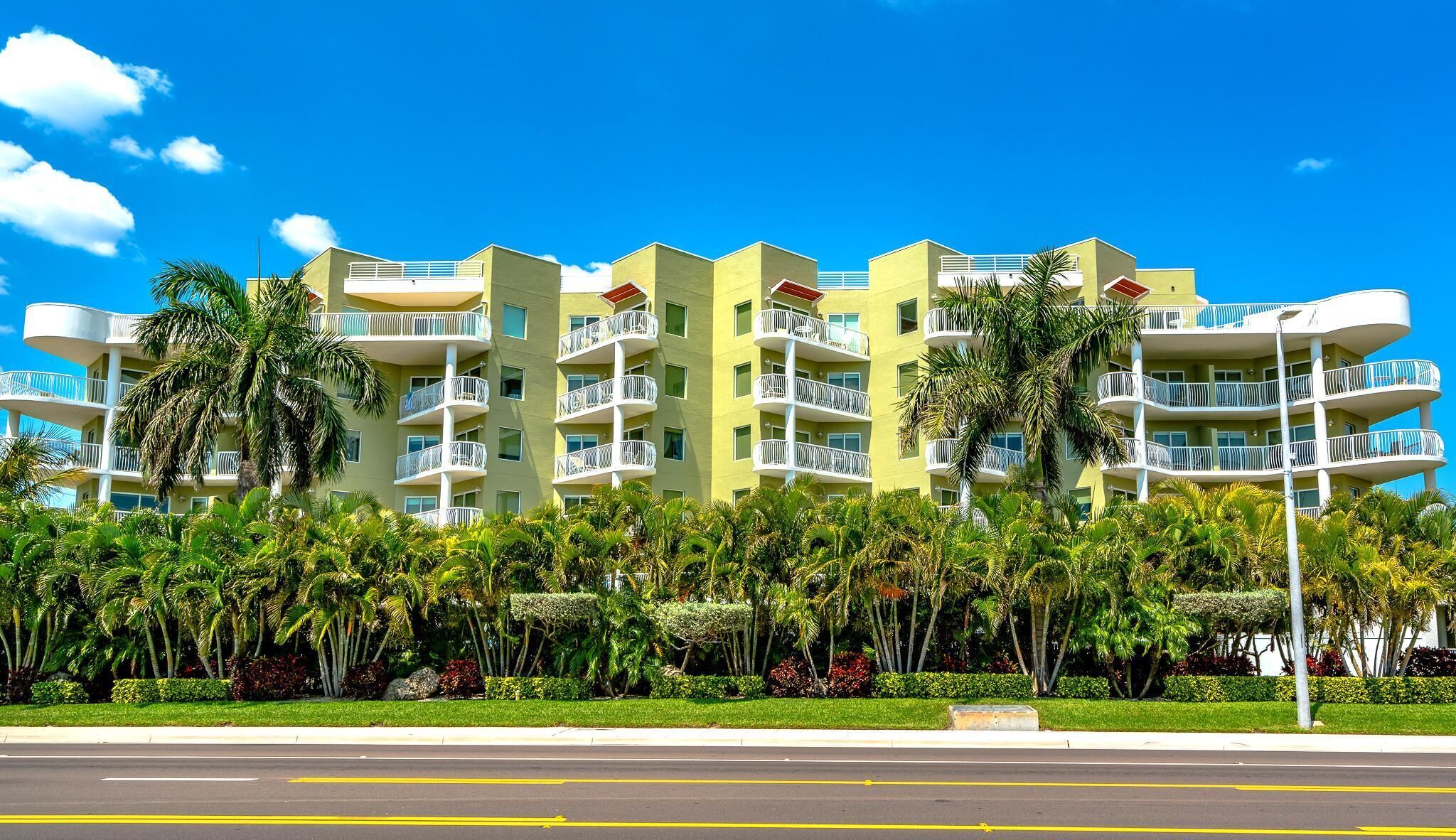 A multi-story hotel with balconies, surrounded by lush greenery and palm trees.