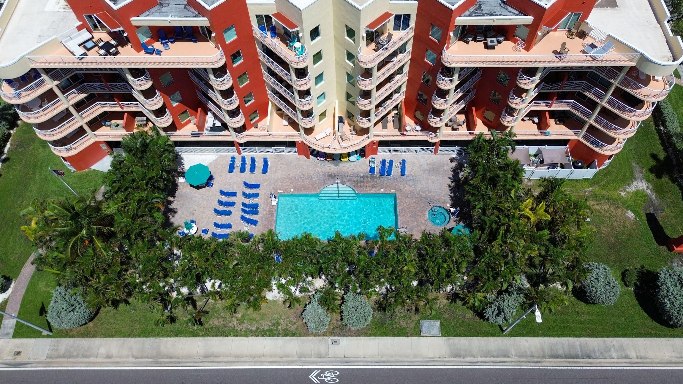 A multi-story hotel with balconies, a swimming pool, and a landscaped garden.