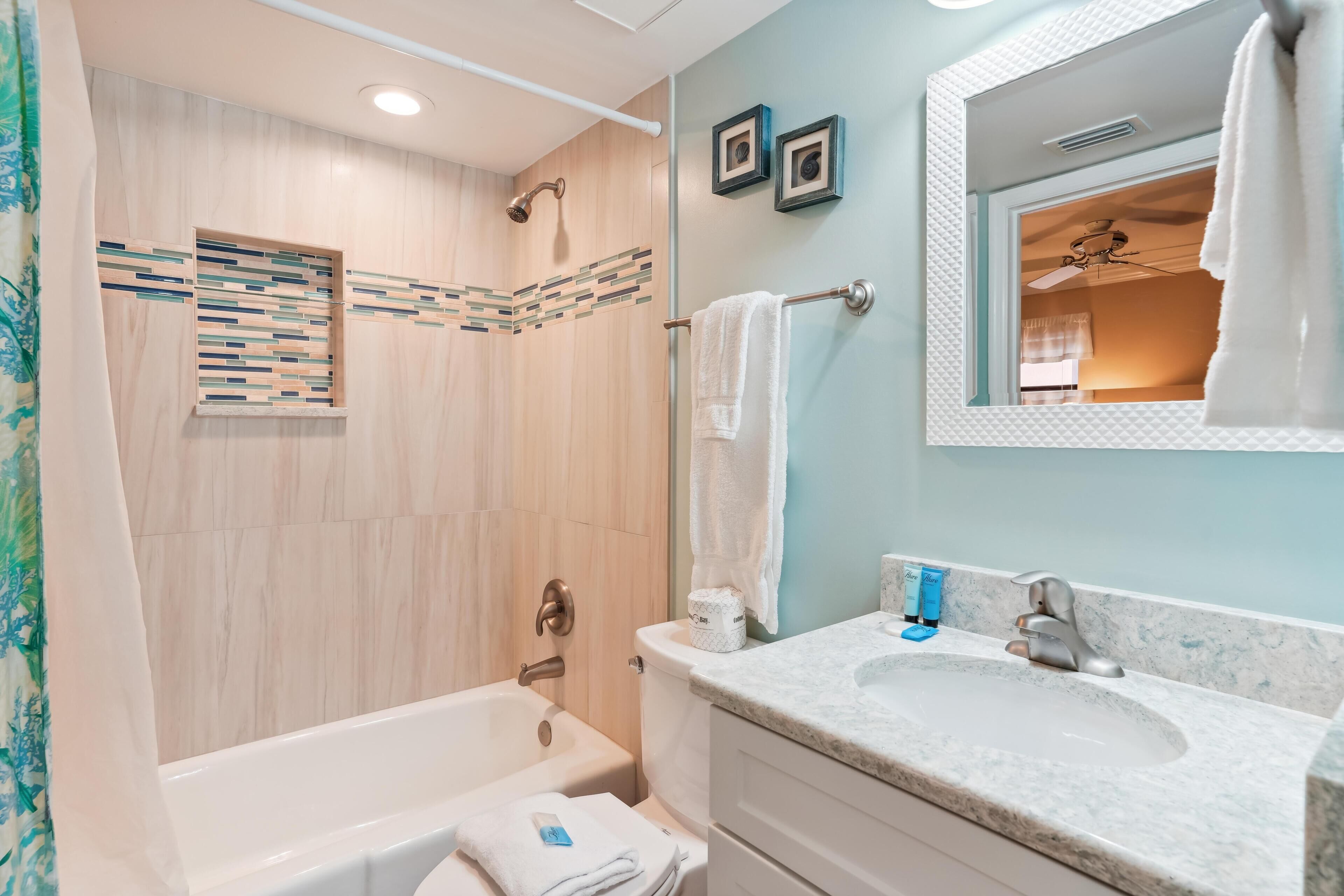A bathroom with a bathtub, a sink, and a shower. There are towels and toiletries on the counter.