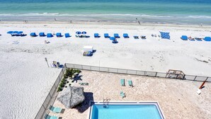 Ein Strandresort mit Schwimmbad, Liegestühlen und einer Holzterrasse.
