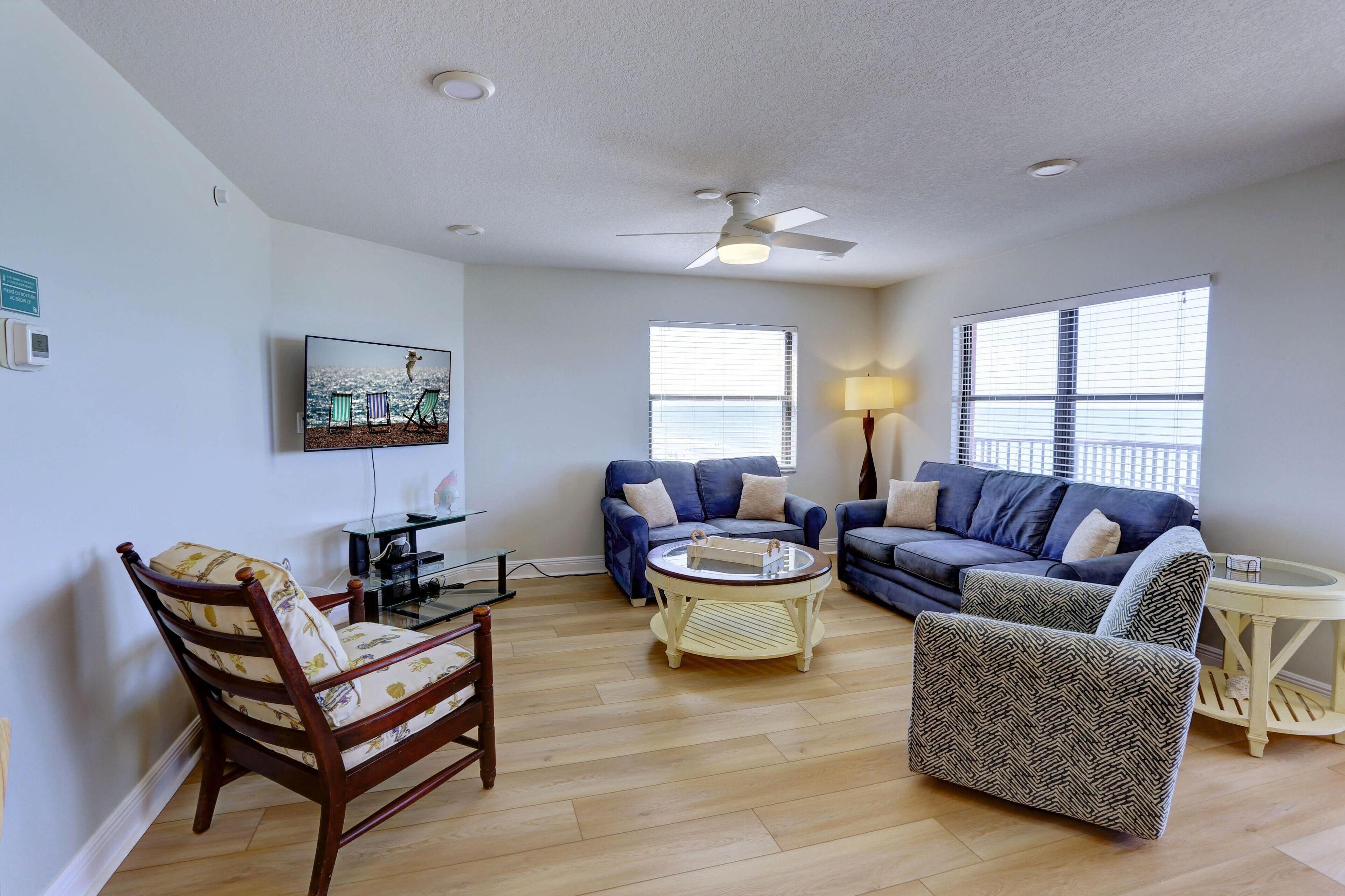 A living room with two sofas, a wooden chair, a round coffee table, and a ceiling fan.