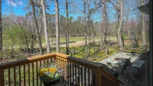 A wooden deck with a view of a forest and a golf course.