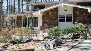 A stone house with a number 26 garage door, surrounded by a garden with rocks and plants.